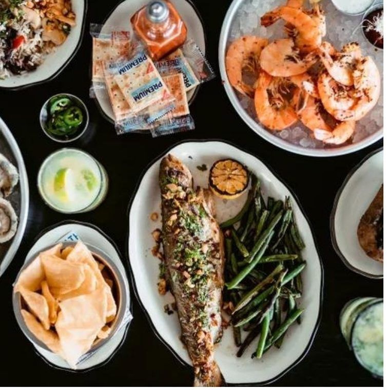 Grilled whole fish, shrimp and sides on a dark table