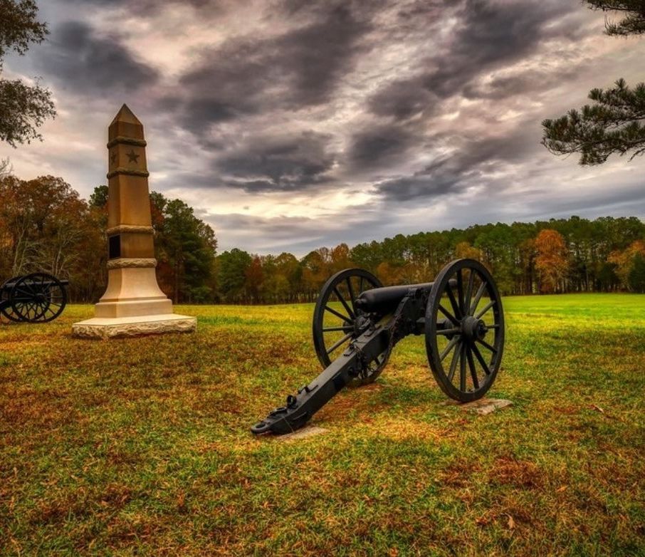 A cannon and stone monument on the Chickamauga battlefield under a stormy sky