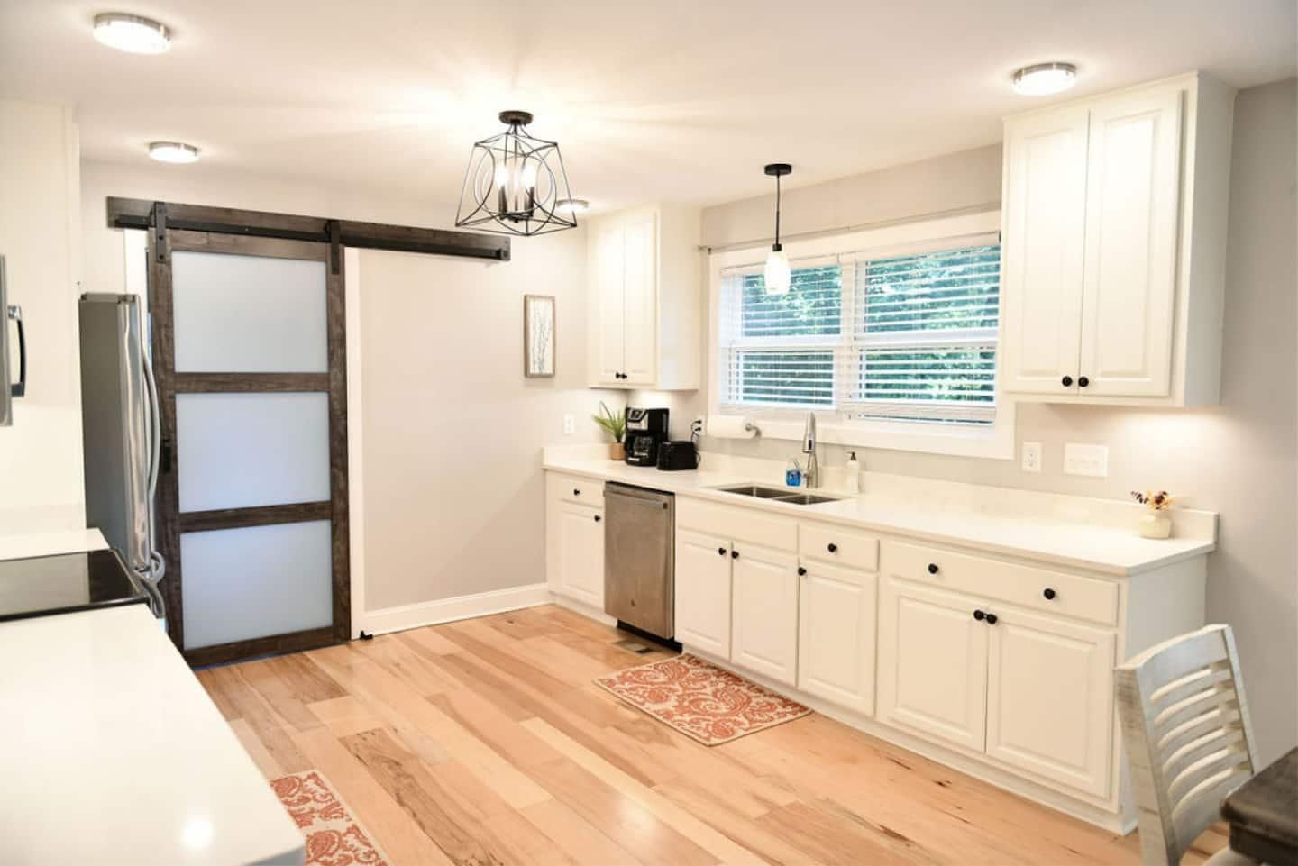 White kitchen with stainless appliances and a sliding barn door