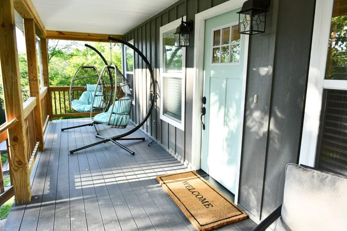 The covered front porch with hanging egg chairs and a mint-green front door