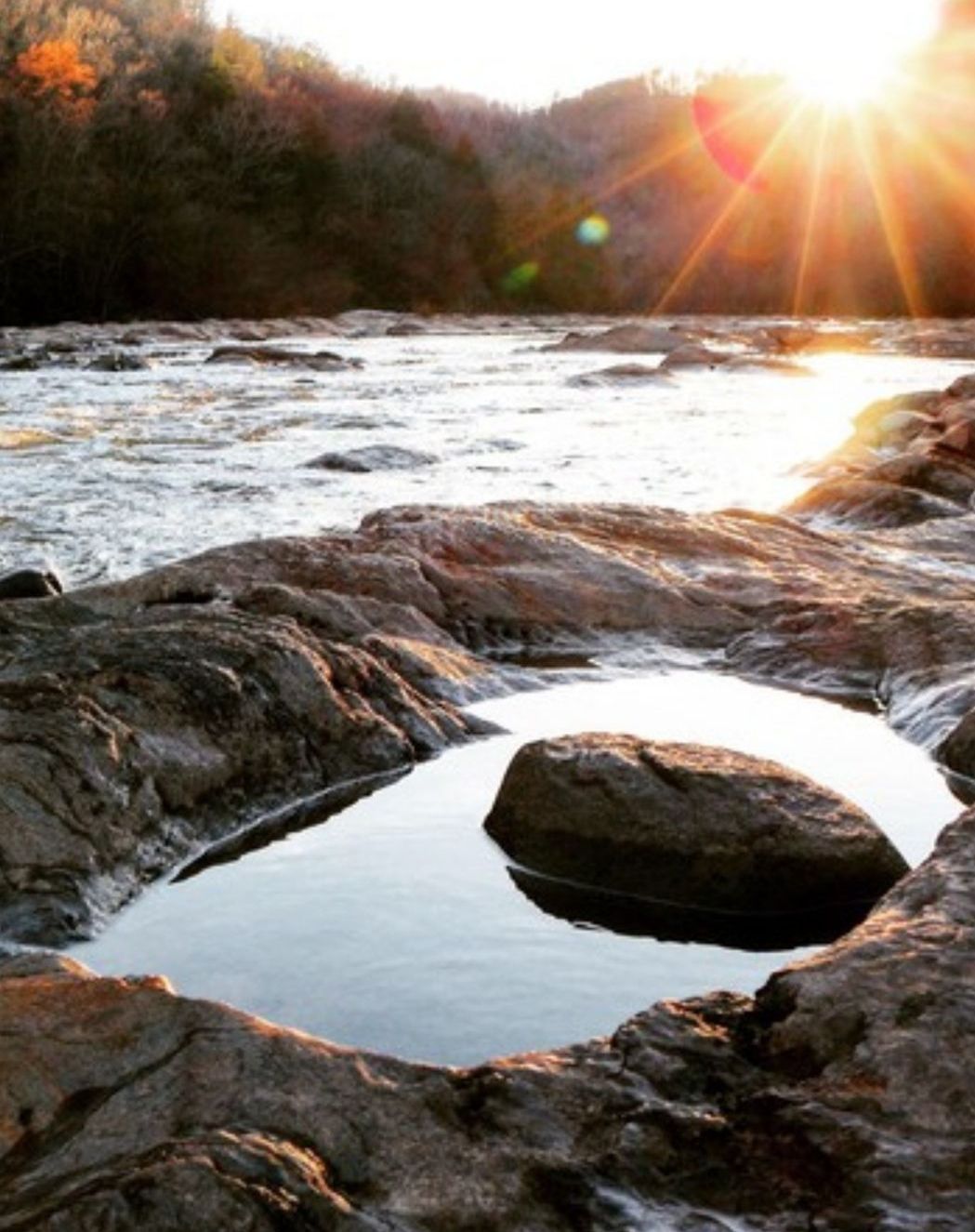 Sun setting over a rocky river in the mountains