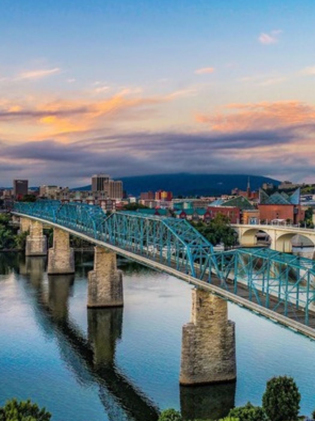 The blue Walnut Street pedestrian bridge over the Tennessee River at sunset